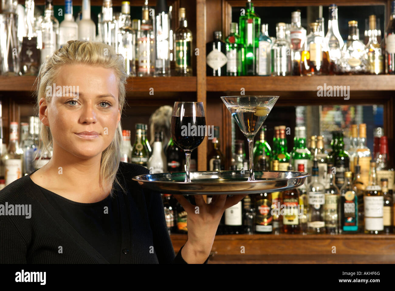 Bar-Mädchen mit einem Martini auf ein Tablett steht vor einer Bar in London. Stockfoto