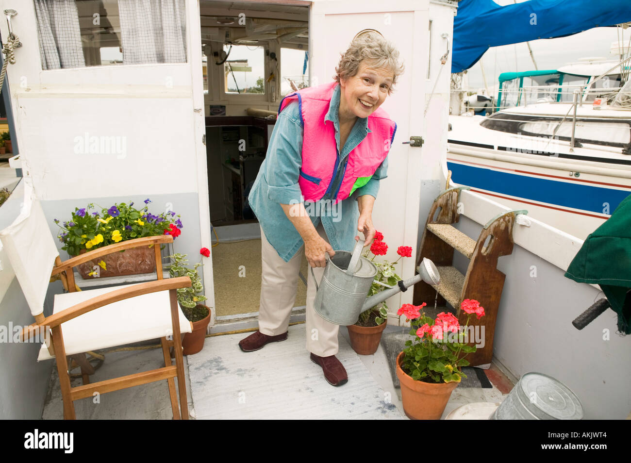 Frau auf Hausboot Bewässerung von Pflanzen Stockfoto