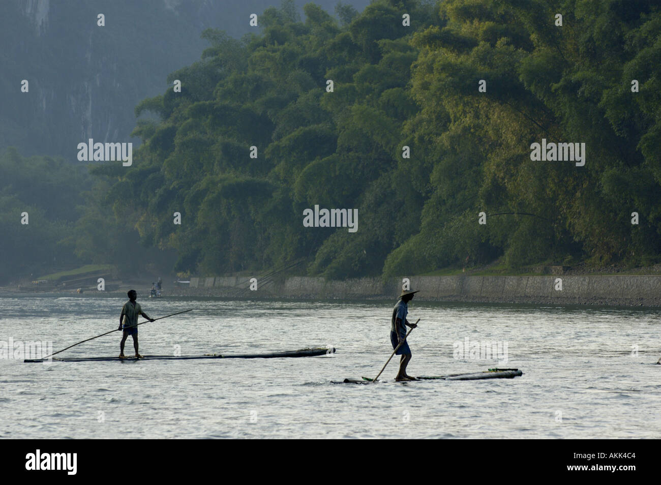 China Guangxi zwei Bauern auf ihre Bambus-Flößen bei Sonnenuntergang zwischen Xinping und Yangshuo am Li Jiang River Navigation Stockfoto