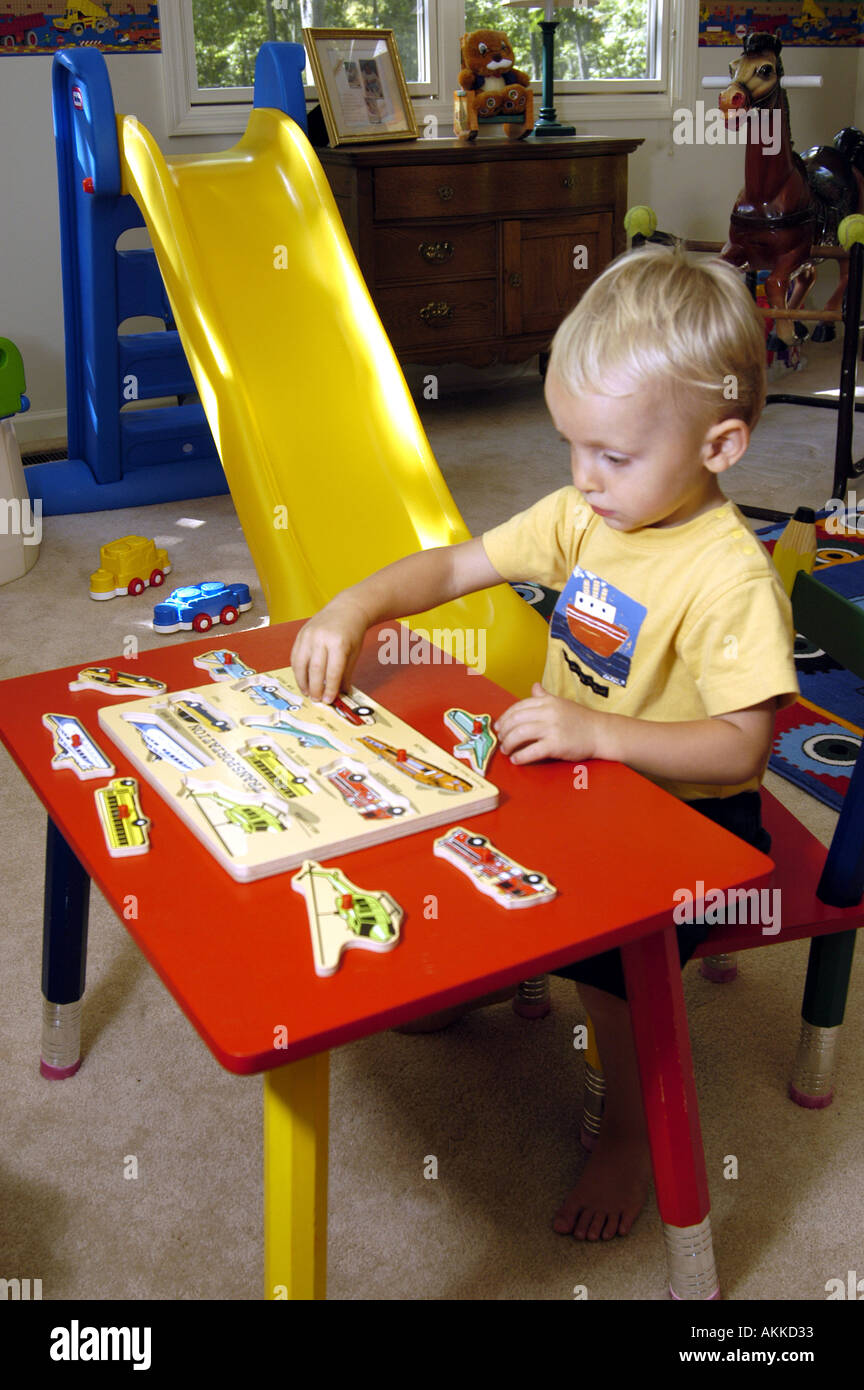 2 Jahre alter Junge arbeitet mit Holzpuzzle in seinem Schlafzimmer Stockfoto