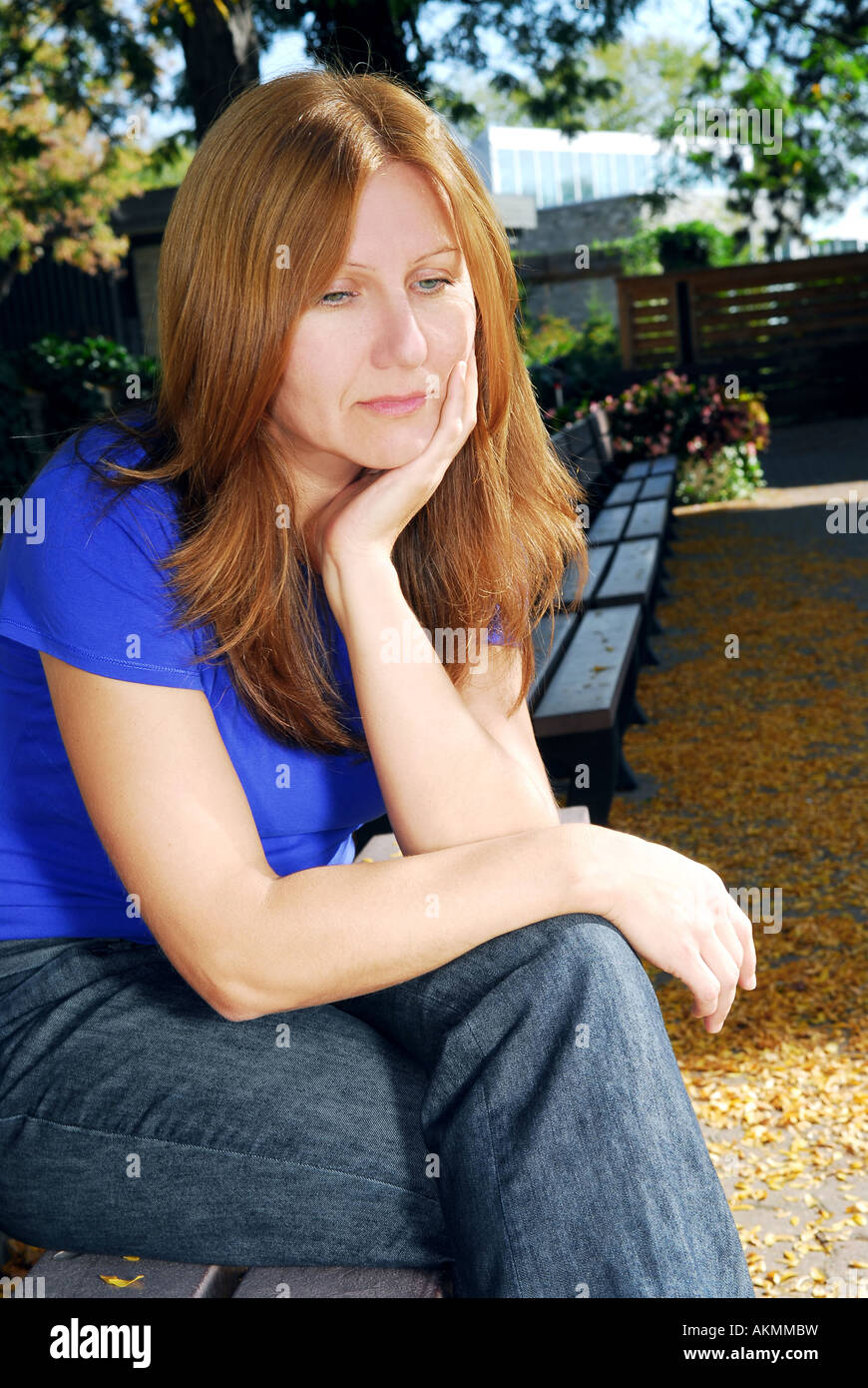 Reife Frau suchen traurig und gestresst sitzt auf einer Parkbank Stockfoto