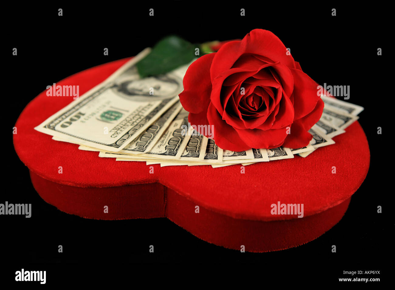 Hundert-Dollar-Scheine auf rotem Samt Valentine Herz mit Rosen isoliert auf schwarz Stockfoto