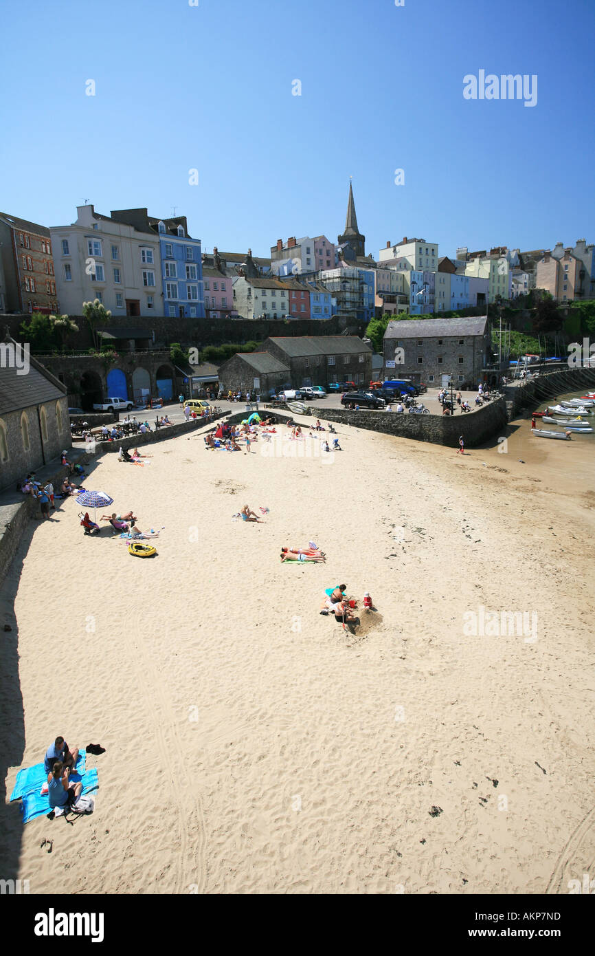 Touristen genießen die Sonne am Hafenstrand Tenby überragt von den berühmten Pastell gemalt Hotels und Häuser Pembrokeshire Wales UK Stockfoto