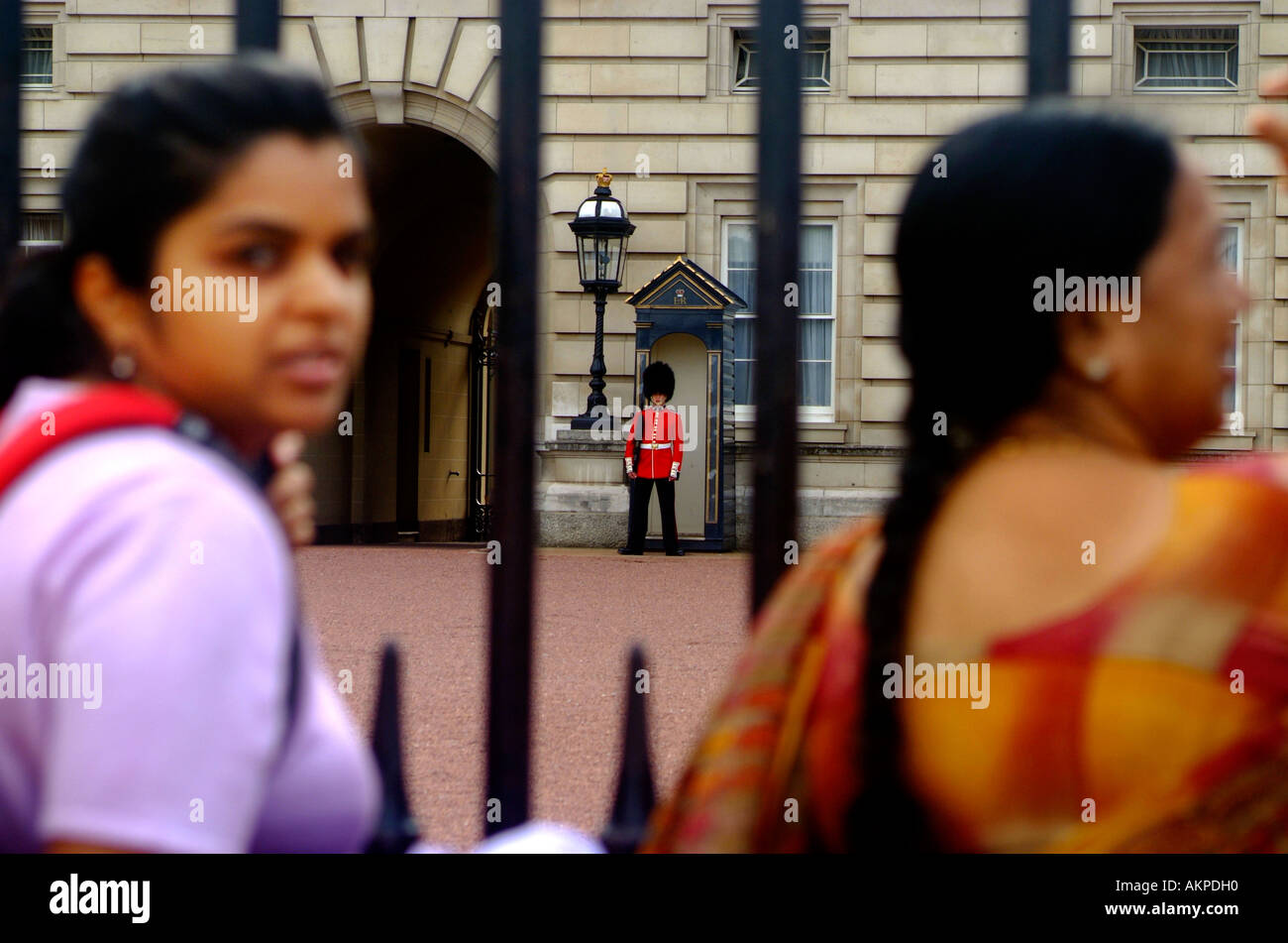 Zwei Hindu-Frau steht außerhalb Buckingham Palast während ein Soldat der Haushalt Garde hinter Stockfoto