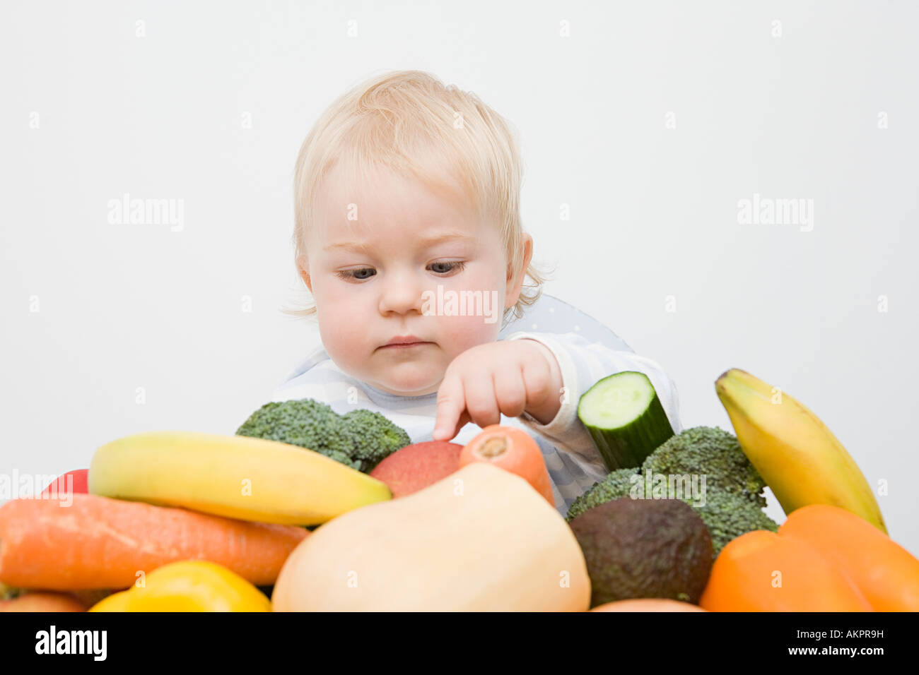 Einen kleinen Jungen, der Blick auf einen Stapel von Obst und Gemüse Stockfoto