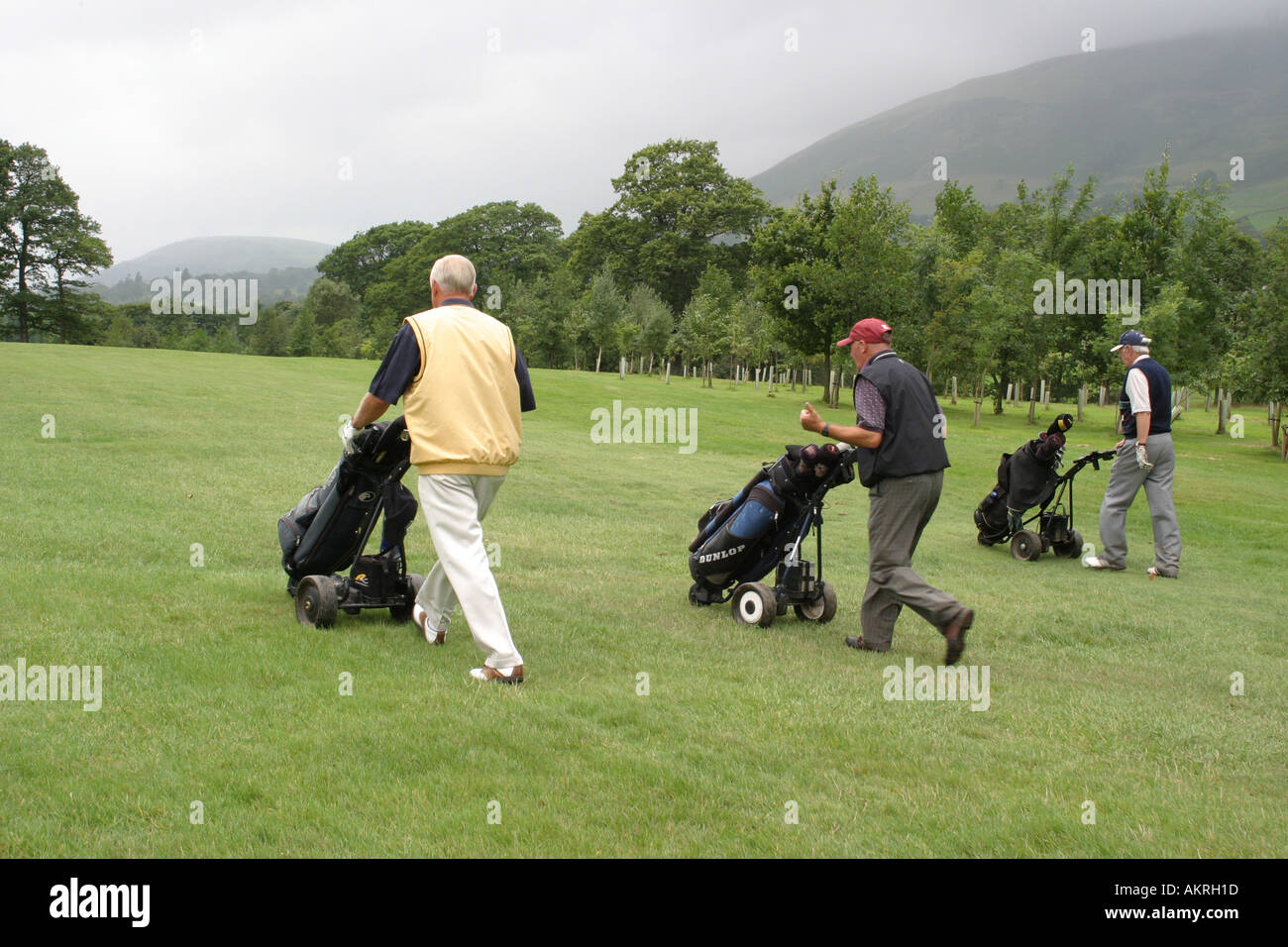 drei männliche Golfer zu Fuß entlang der Fahrrinne, ihre Kugeln zu erreichen Stockfoto