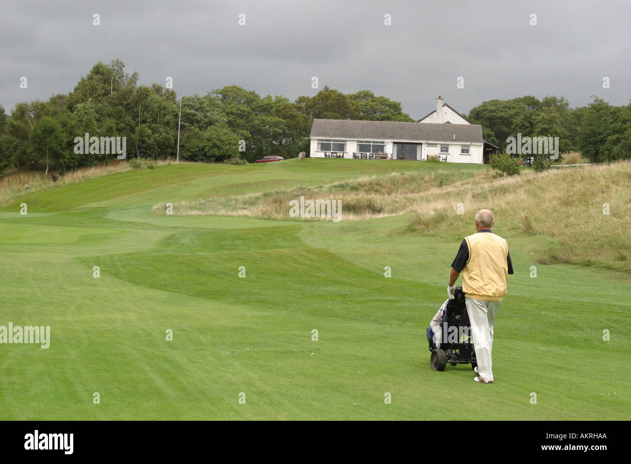Golfer drängen Tasche entlang Fairway, green, wo sein Ball ist Stockfoto