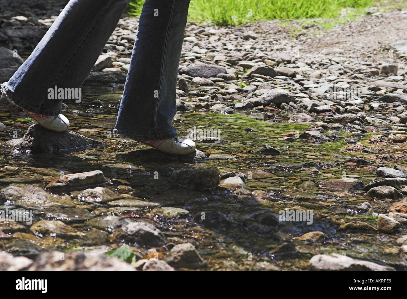 Mädchen über einen Fluss auf Kieselsteinen weichen Stockfoto