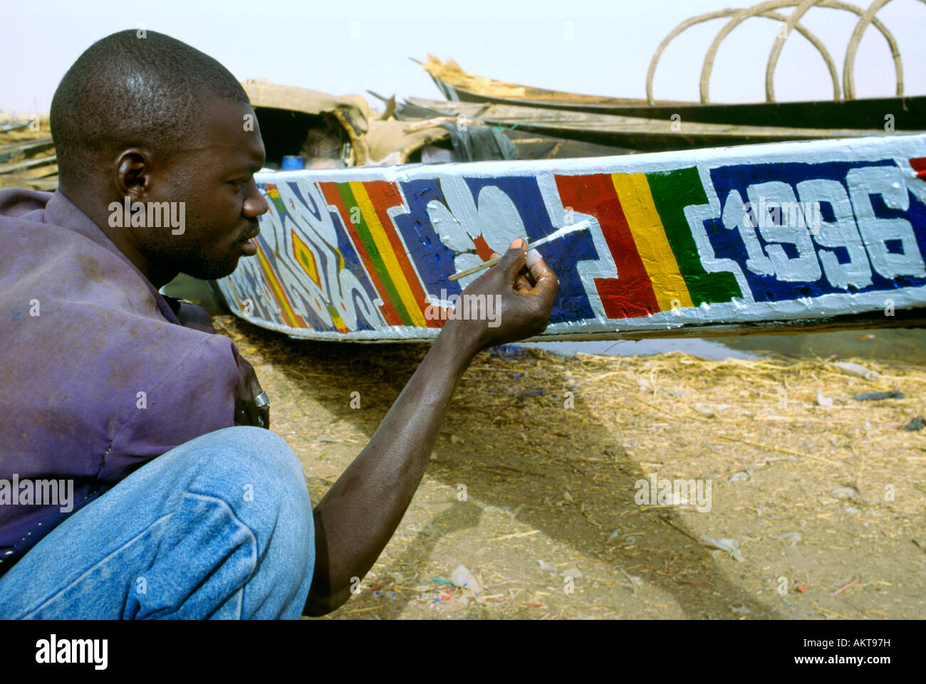 Ein Fluss Niger Schiffer malt den Bogen seines Bootes Stockfoto