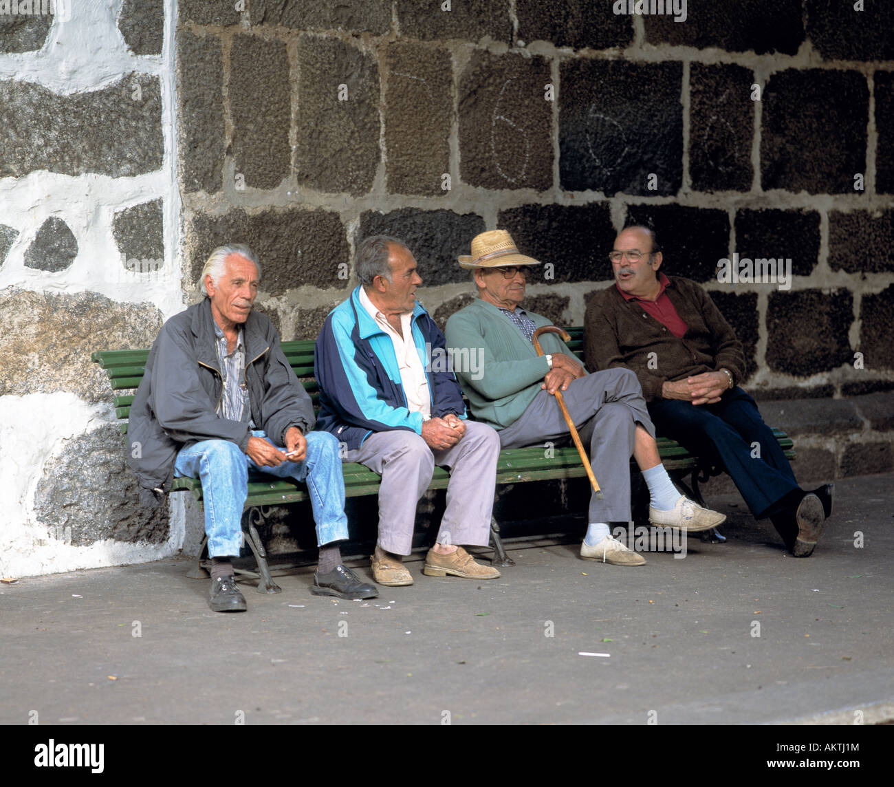 Spanien, Kanarische Inseln, La Palma, Rede, Gespräch, Diskussion, Rentner, Senioren, einheimische, vier ältere Männer sitzen auf einer Bank vor einer Felswand im Gespräch Stockfoto