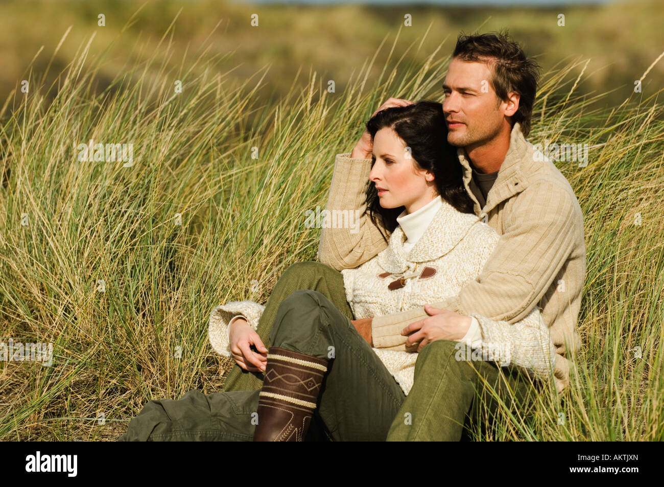 Junges Paar sitzt in Dünen, umarmen Stockfoto