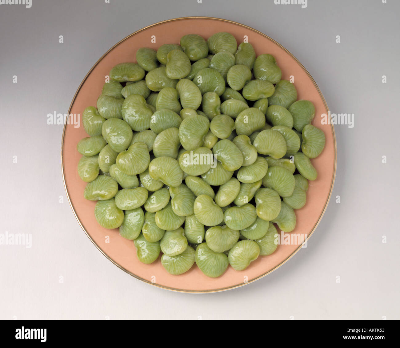 gefrorenes Gemüse grüne Limabohnen auf rosa Goldrand Teller Bon Appetit Stockfoto