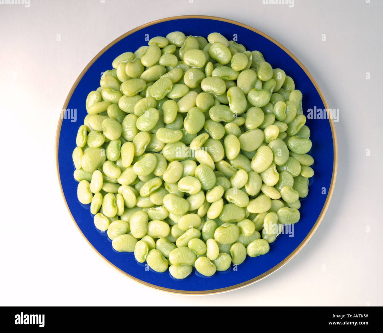 kleines Baby grün Limabohnen auf blau Goldrand Teller Tiefkühlgemüse Bon Appetit Butterbohnen Stockfoto