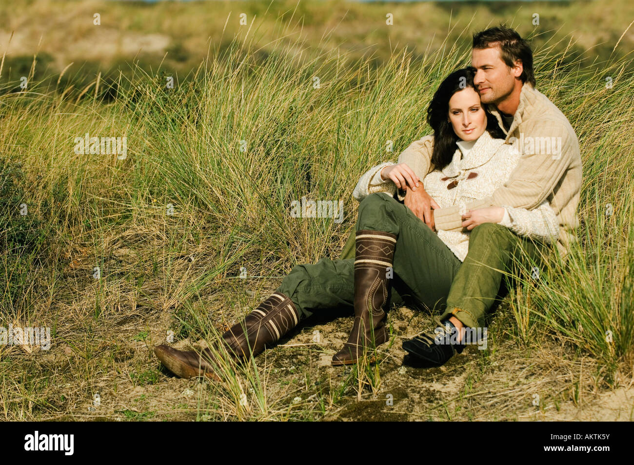 Junges Paar sitzt in Dünen, umarmen Stockfoto