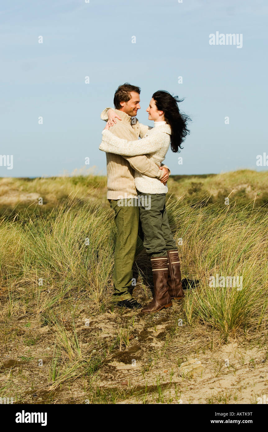 Paar steht in Dünen, umarmen, Seitenansicht Stockfoto