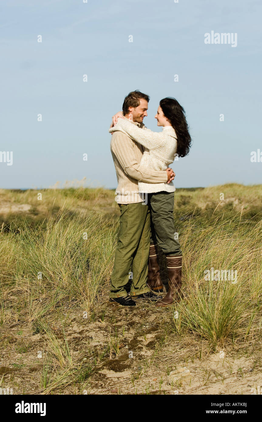 Paar steht in Dünen, umarmen Stockfoto