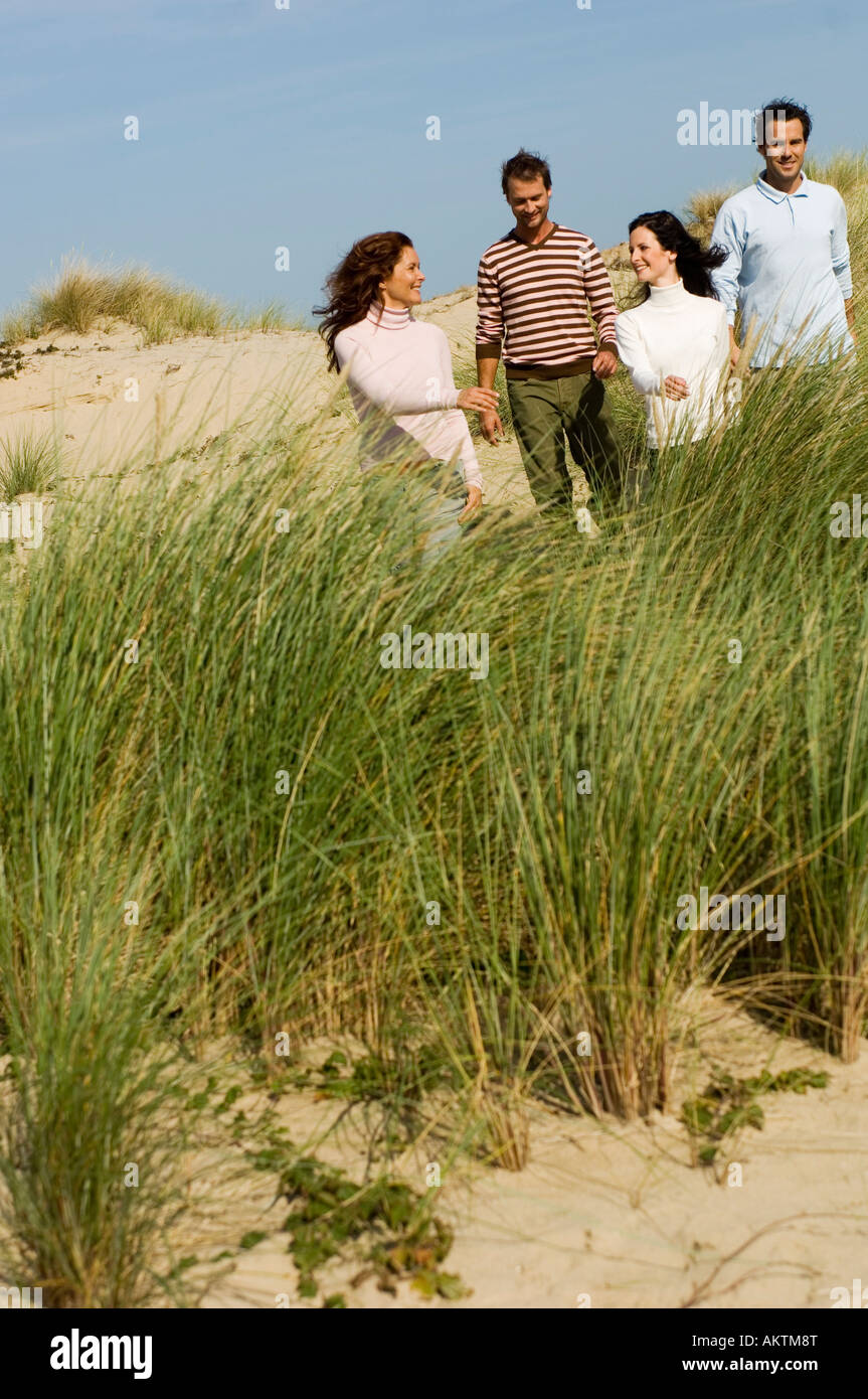 vier Freunde, die zu Fuß am Strand Stockfoto