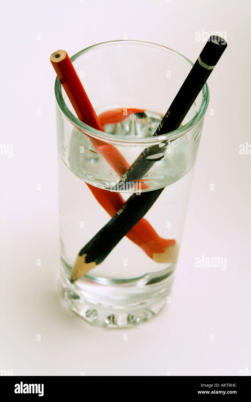 Zwei Stifte in einem Glas Wasser zeigt die optische Distoprtion, verursacht durch Brechung des Bildes Stockfoto