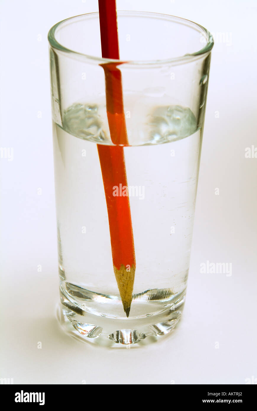 Ein Bleistift in ein Glas Wasser zeigt die optische Distoprtion, verursacht durch Brechung des Bildes Stockfoto