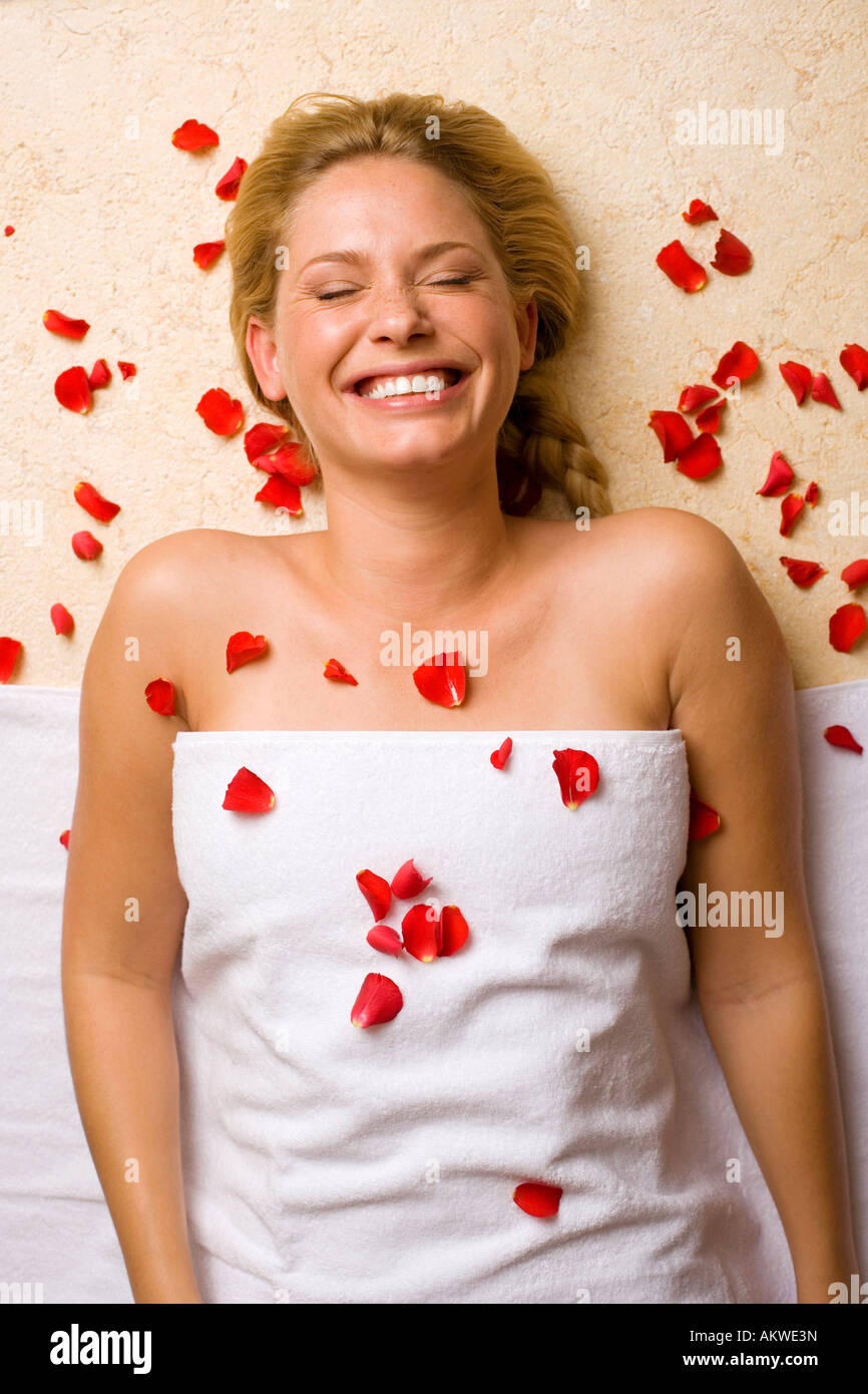 Deutschland, junge Frau liegend auf Massagetisch, Blütenblätter auf Brust Stockfoto