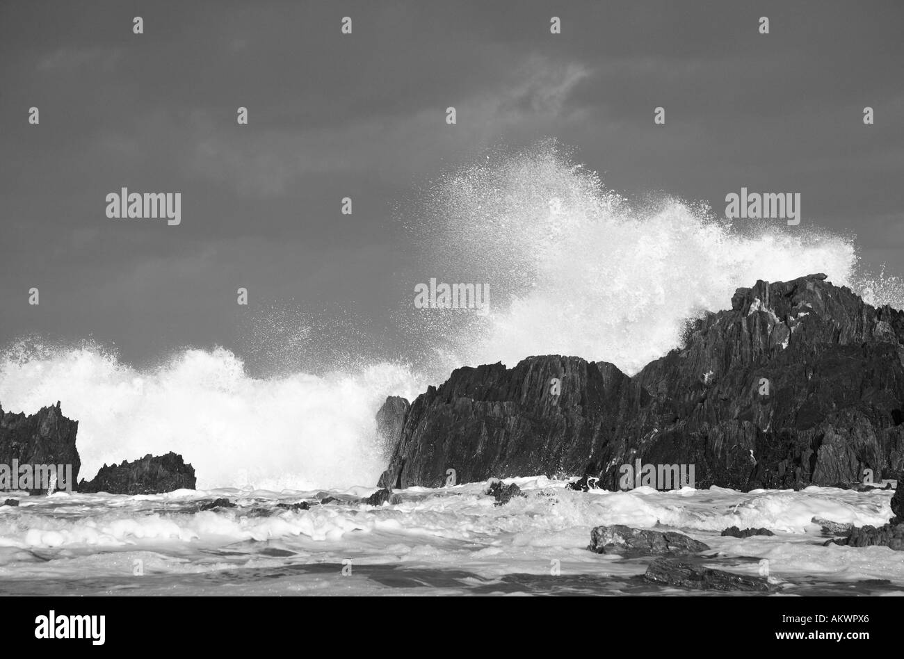 eine riesige Welle trifft Felsen am Ufer Stockfoto