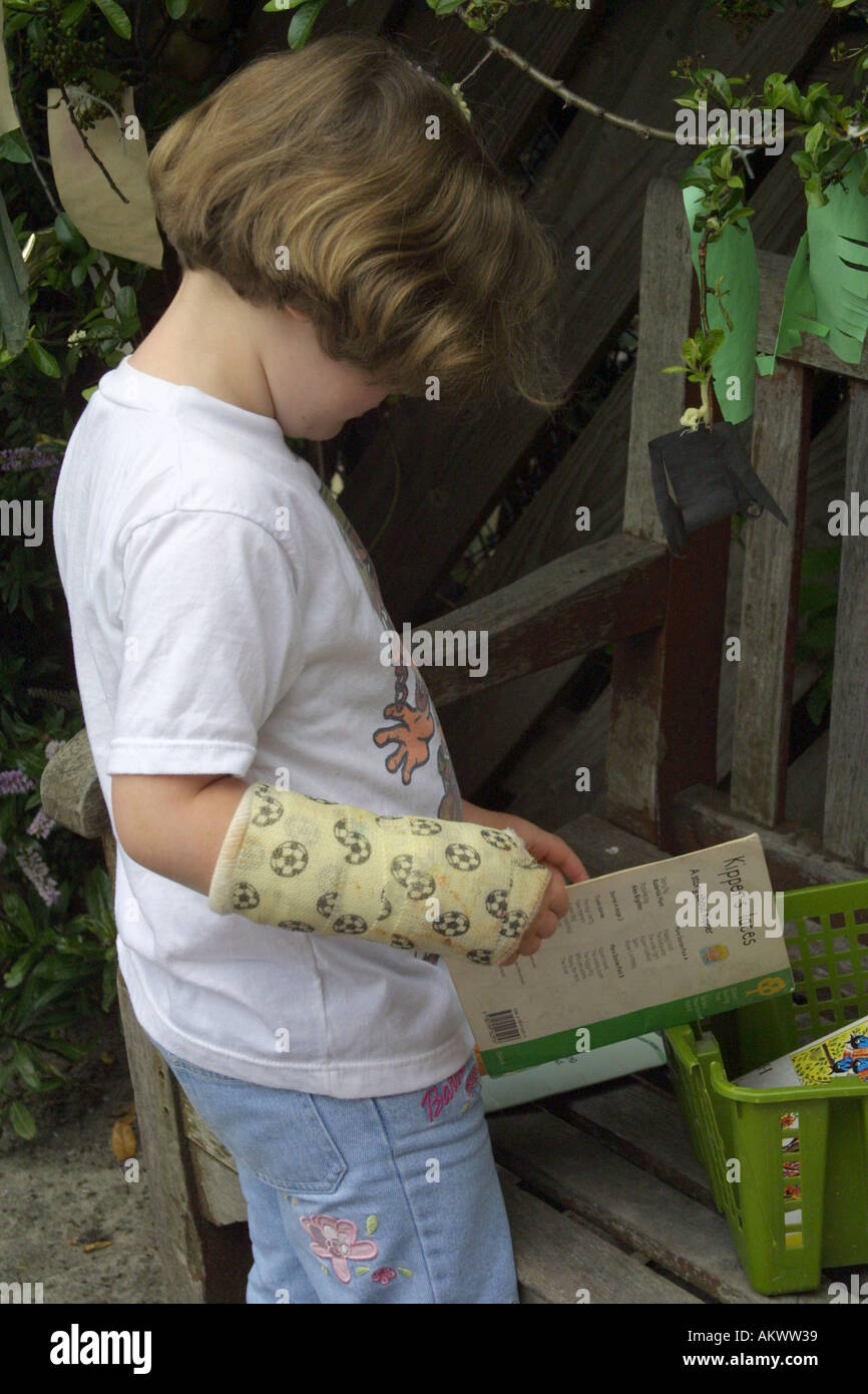 junges Mädchen mit einem Arm in Gips zu lesen Stockfoto