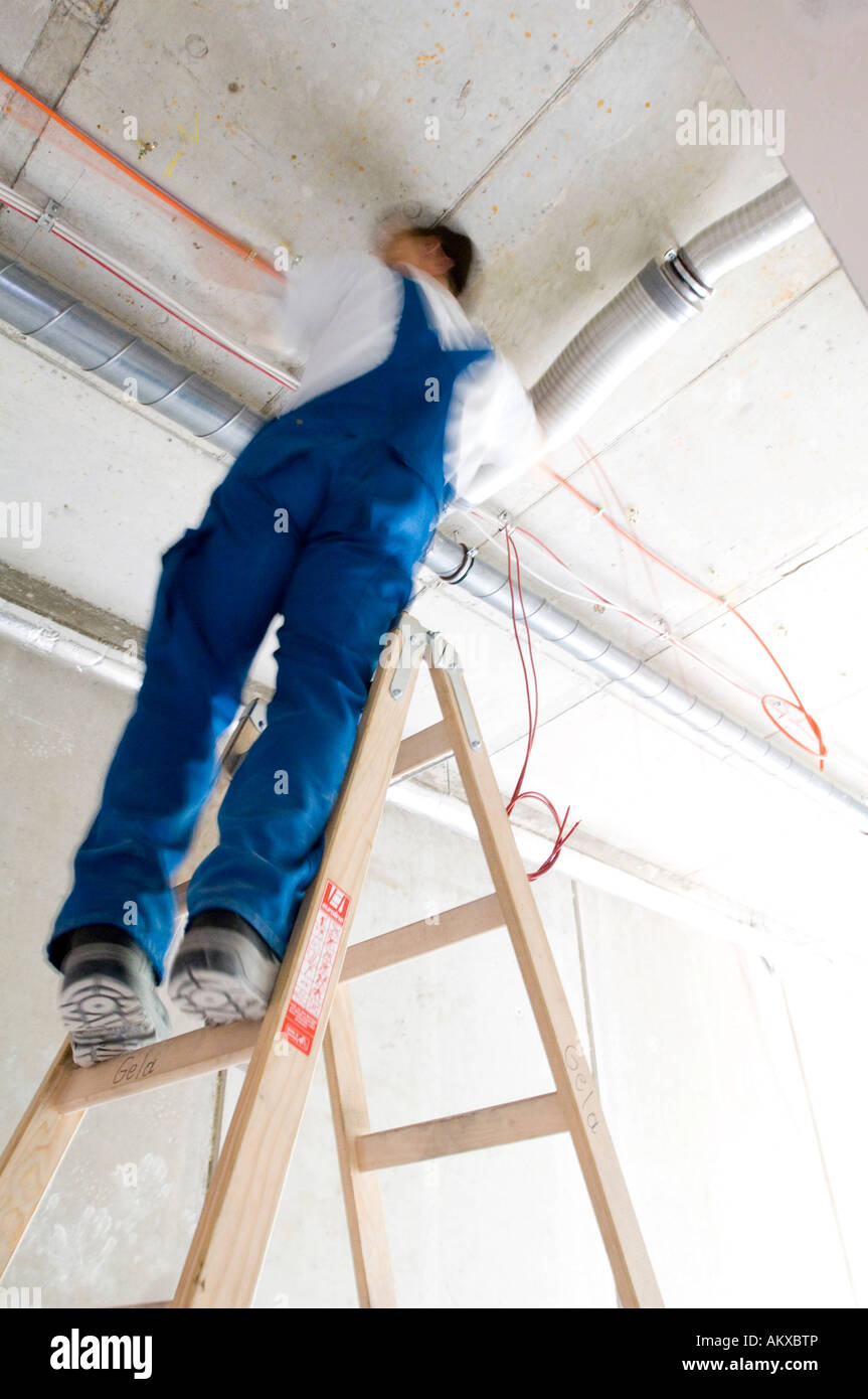Bauarbeiter legt Kabel an der Decke Stockfoto