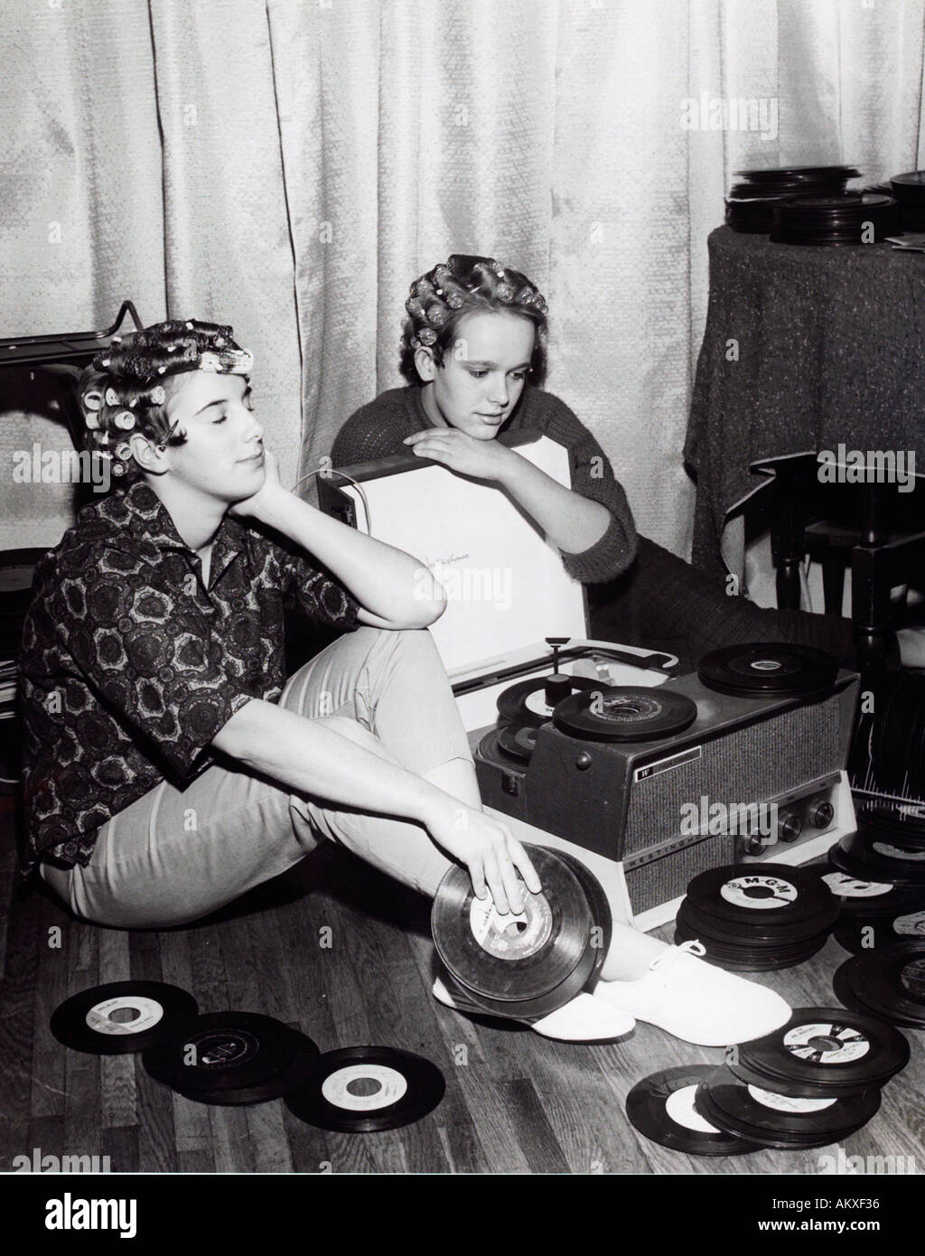 Zwei Mädchen im Teenageralter in Lockenwickler verträumt anhören 45 u/min Aufzeichnungen auf dem Vintage Plattenspieler zu Hause in der 1950 s Stockfoto