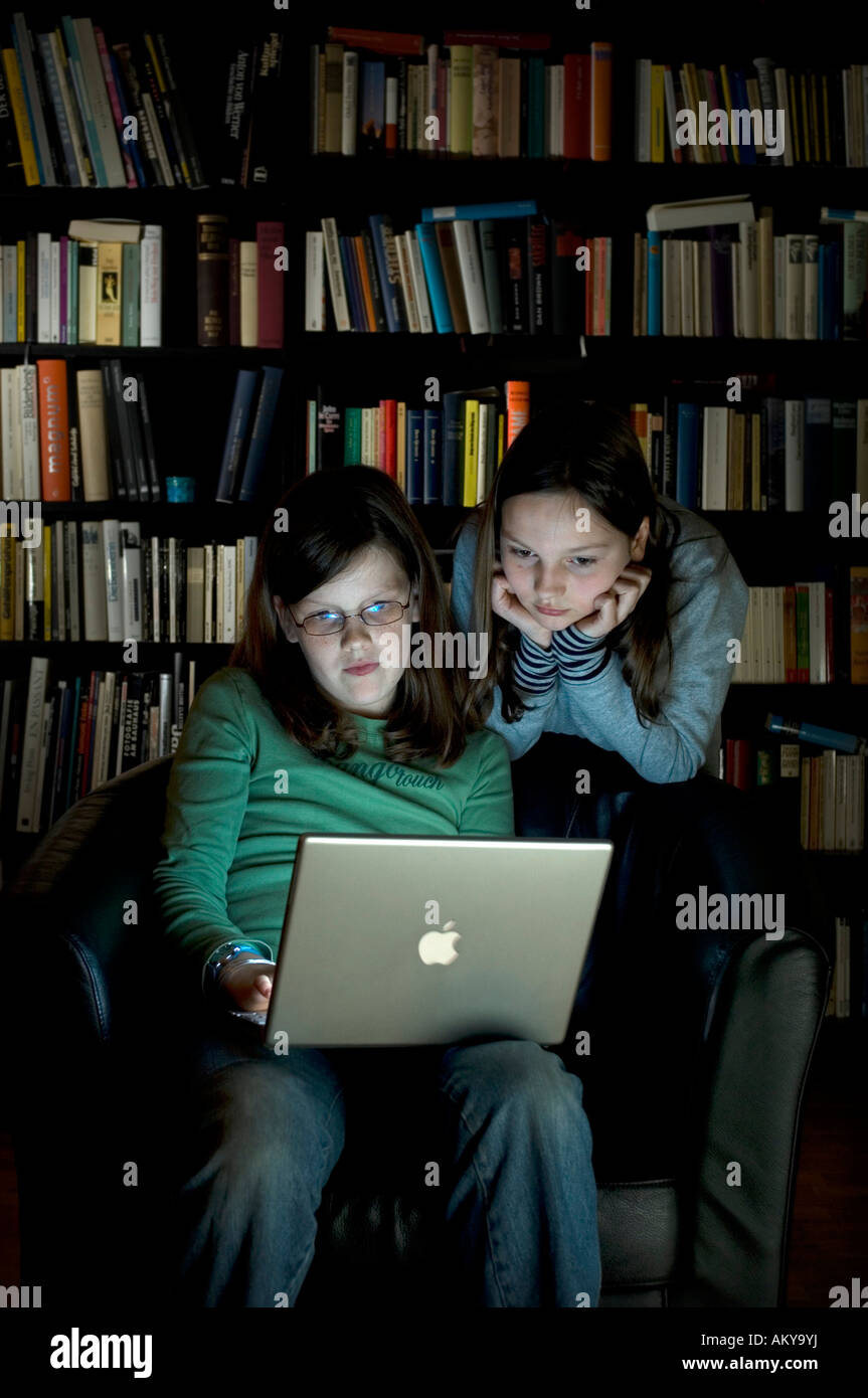 10 Jahre alten Mädchen mit einem Laptop-Computer vor einem Bücherregal Stockfoto