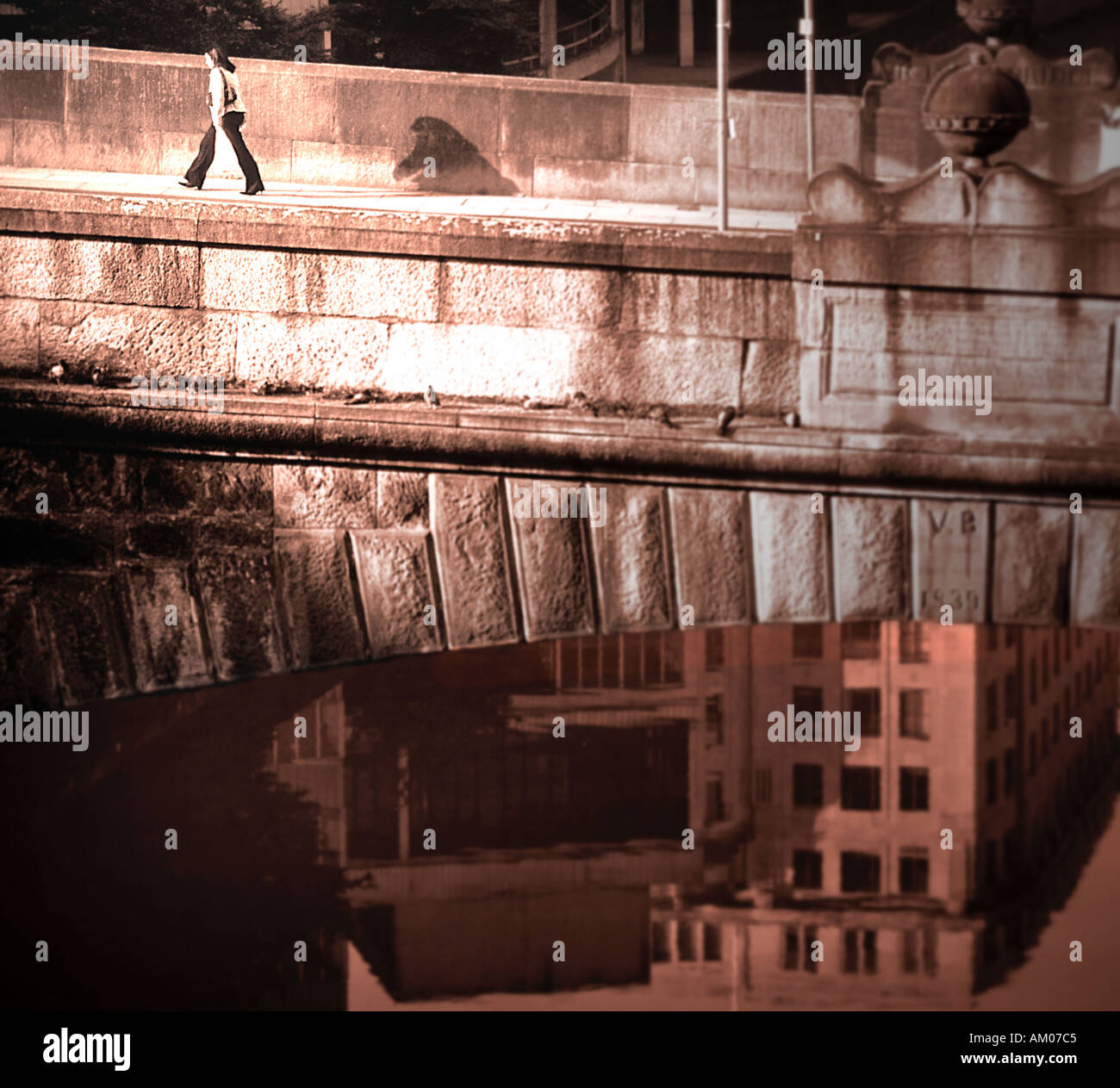 Isolierte Person geht eifrig über große steinerne Brücke mit Reflecton Wasser unter Victoria Bridge Manchester UK Stockfoto