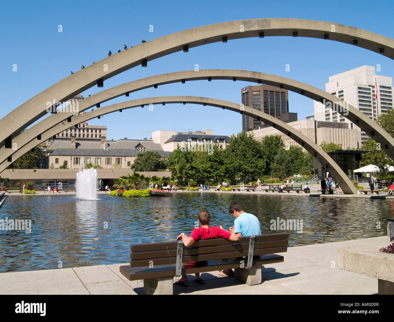 Personen saß neben dem Teich / Eisbahn unter der Freiheit Bögen am Nathan Phillips Square Downtown Toronto Ontario Kanada Stockfoto