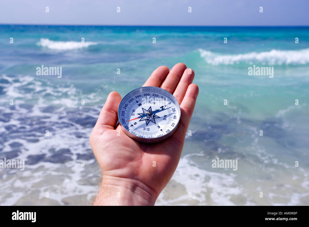 Mans Hand mit Kompass mit Ozean Horizont im Hintergrund Stockfoto