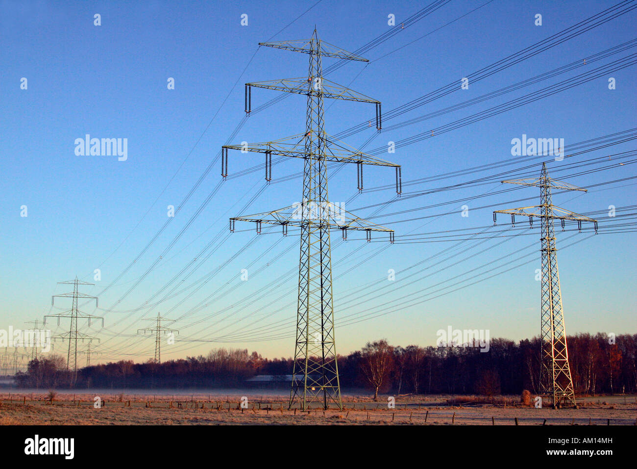 Strommasten - Linien Hochspannung Strom - Sonnenaufgang am Wintermorgen - Schleswig-Holstein, Deutschland, Europa Stockfoto