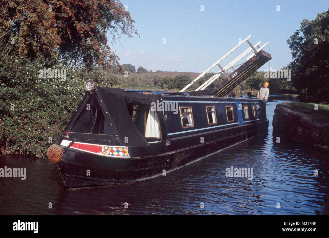 Mann Lenkung Narrowboat durch engen Spalt unter Freischwinger Hubbrücke am Oxford-Kanal, in der Nähe von Thrupp, Oxfordshire, England Stockfoto