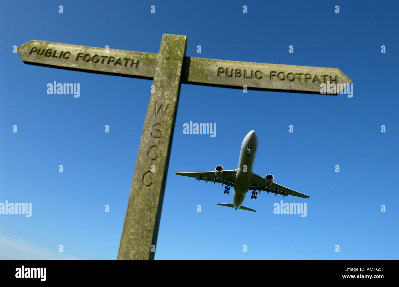 Ein Jet Airliner kommt ins Land am Flughafen London Gatwick über ein Schild, Wanderer, Wanderwege auf angrenzenden landwirtschaftlichen Flächen Stockfoto