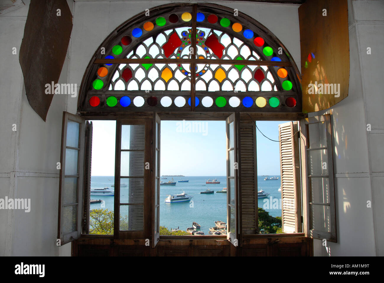 Blick durch die bunten Fenster von Beit el-Sahel Palastmuseum bis zum Meer mit Schiffen Stone Town Sansibar Tansania Stockfoto