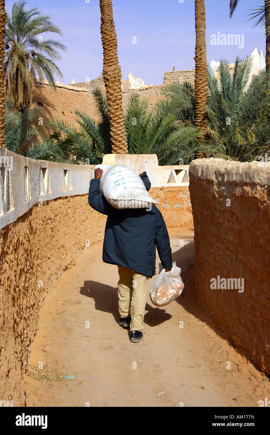 Mann wieder aus dem Markt mit schweren Taschen, alte Stadt von Ghadames Libyen Stockfoto
