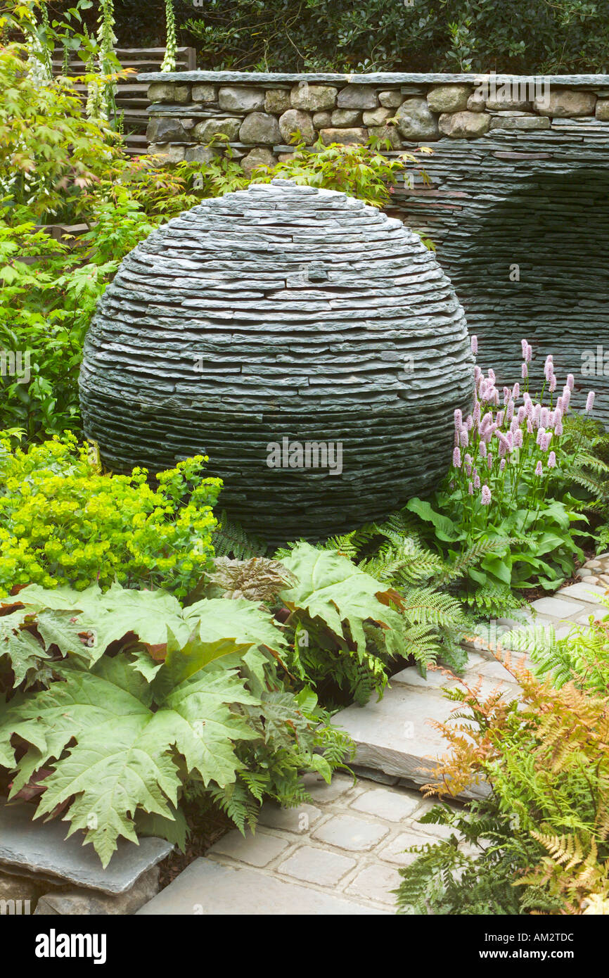 Die Chelsea Flower Show 2005 Stein Kugel mit negativen Bild von sich selbst in Trockenmauer hinter Frühling Zeit Wald Pflanzen Stockfoto