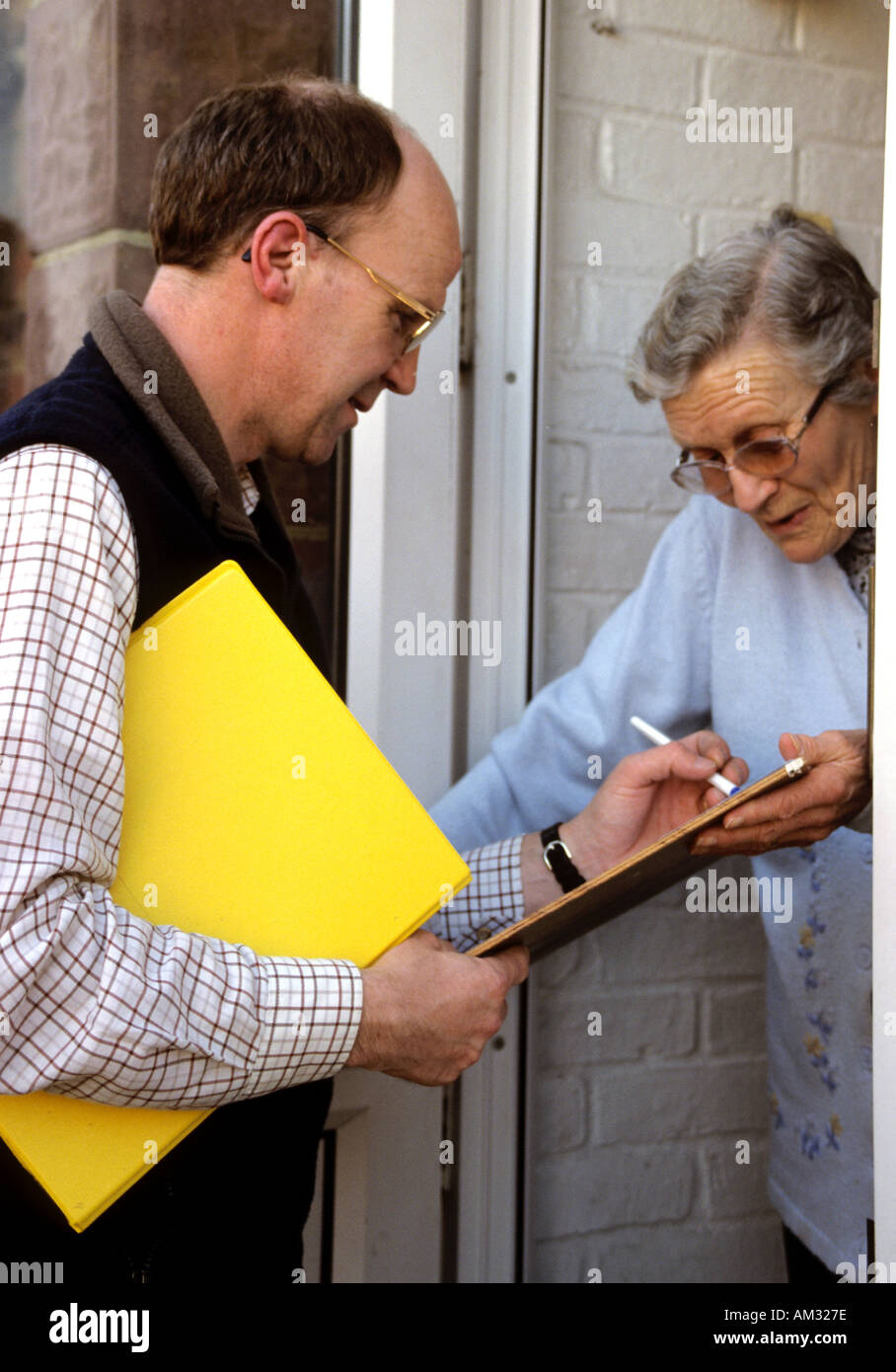 Ältere Frau wird gebeten, etwas zu unterzeichnen durch eine Tür Verkäufer oder Leinwand Stockfoto
