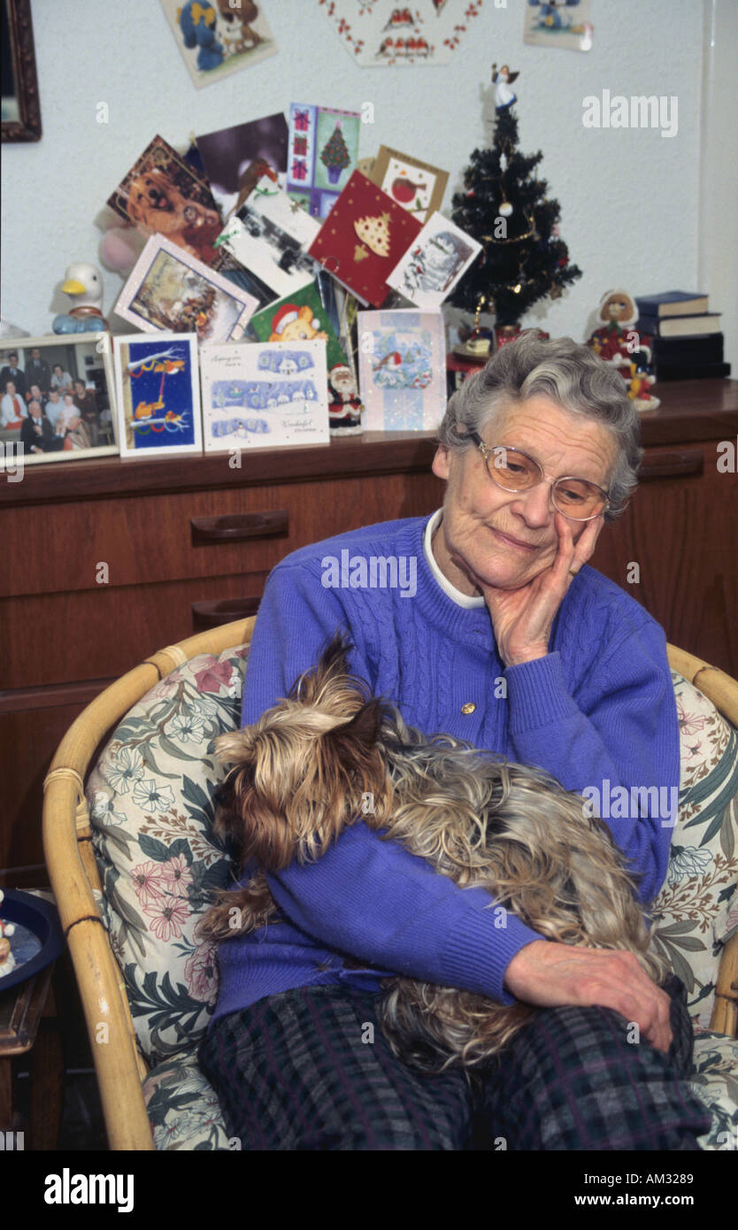 Ältere Dame, die an Weihnachten mit ihrem Hund sitzt traurig Stockfoto