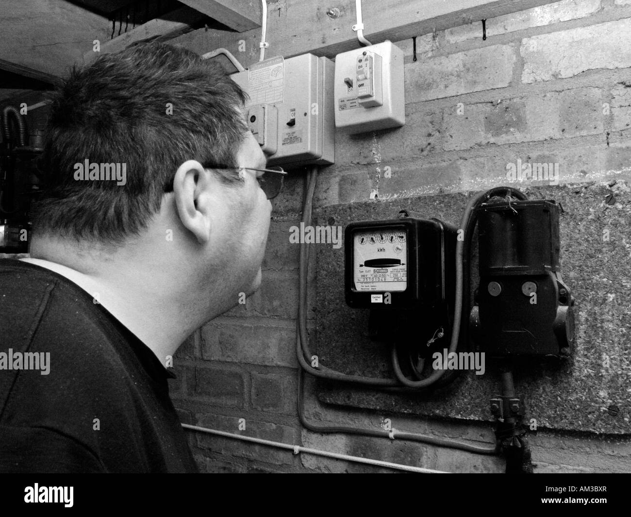 man liest und Überprüfung Stromzähler in garage Stockfoto