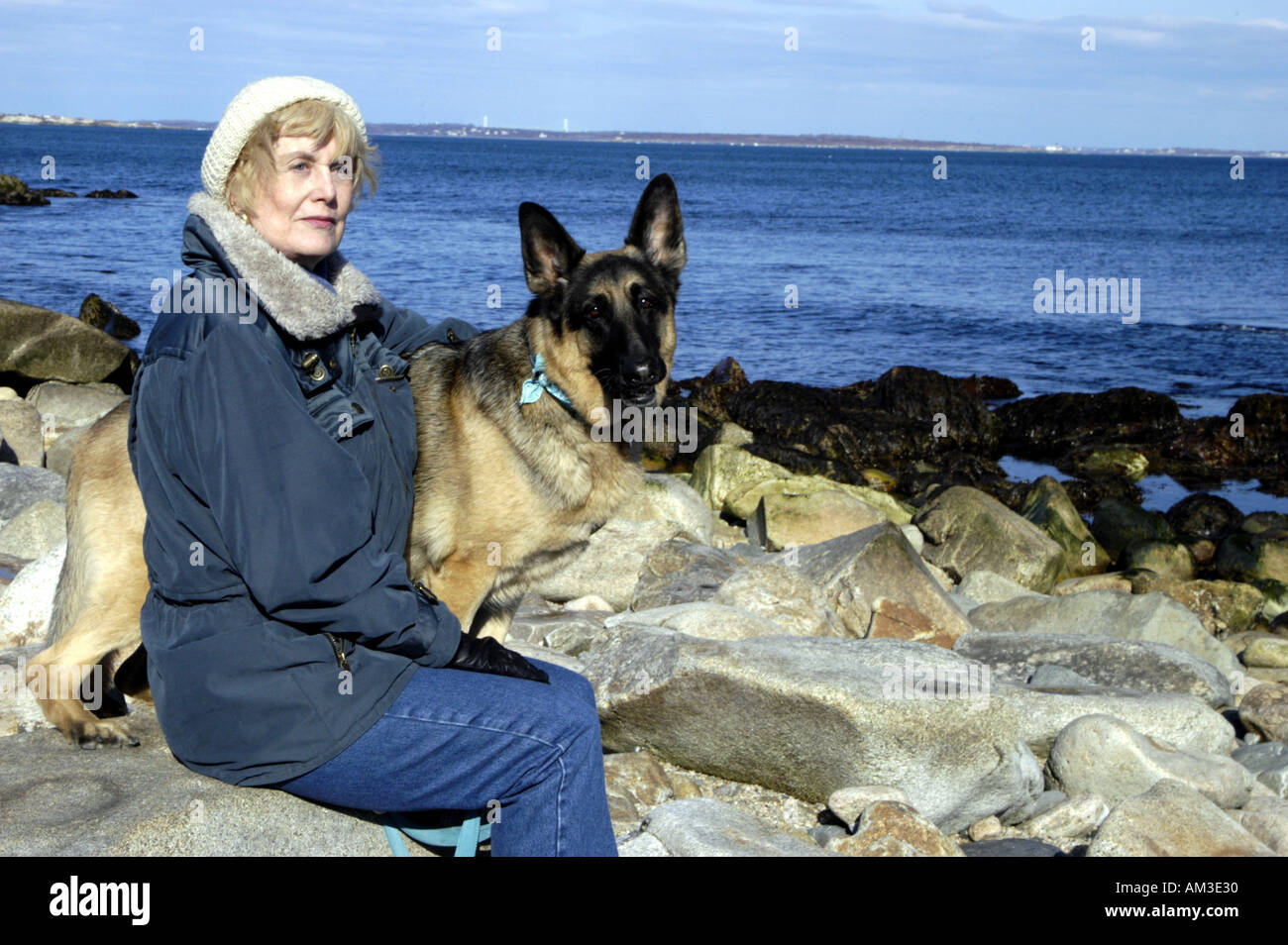 Ältere Frau mit Hund auf Felsenküste Stockfoto
