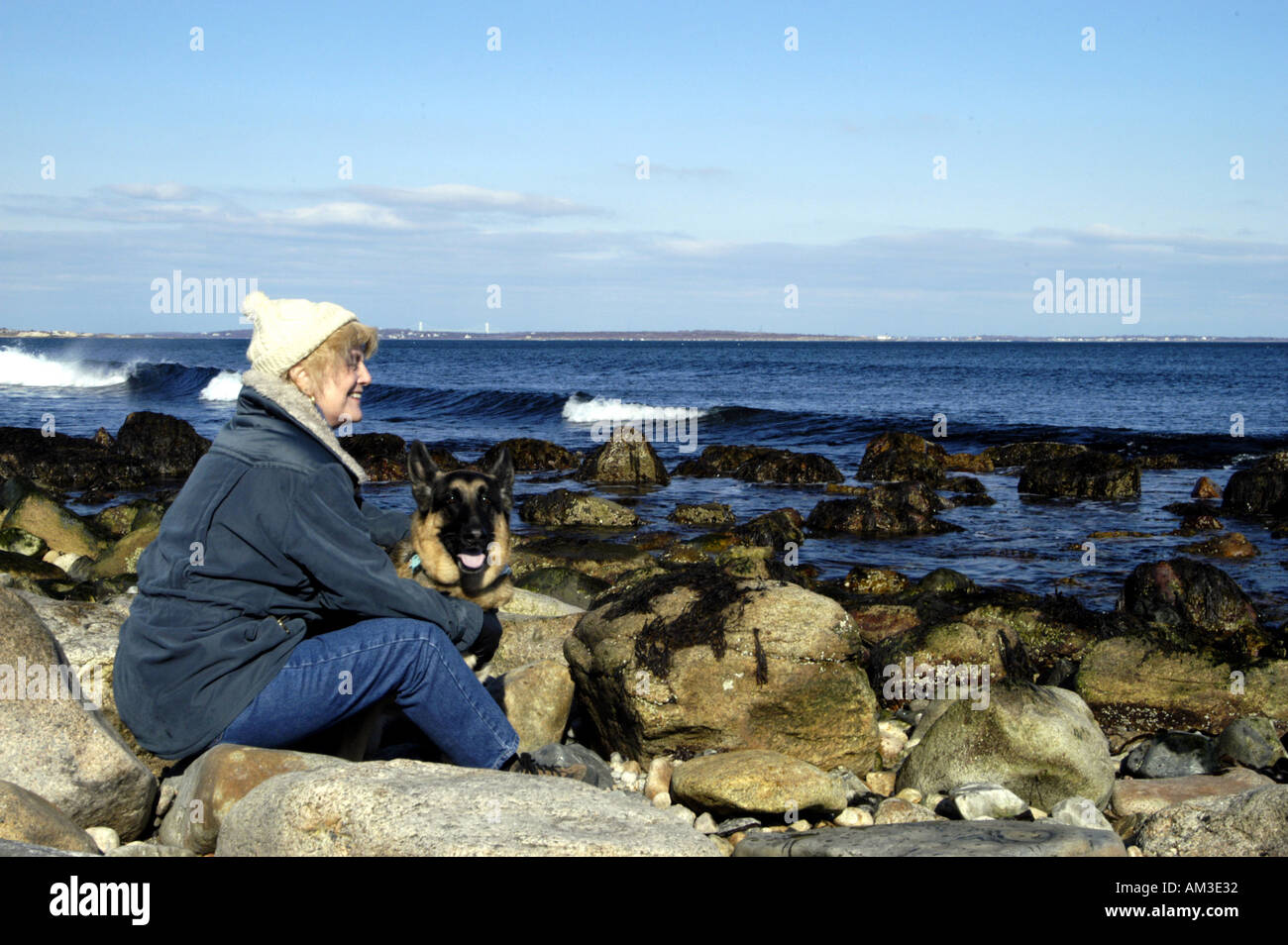 Ältere Frau mit Hund auf Felsenküste Stockfoto