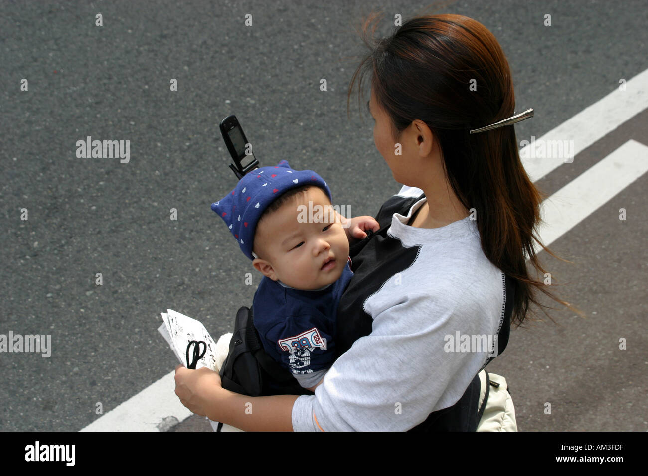 Japanische asiatische Mutter mit jungen Baby prüft ihr Mobiltelefon für e-Mail-Text-Nachrichten in Osaka Kansai Japan Stockfoto