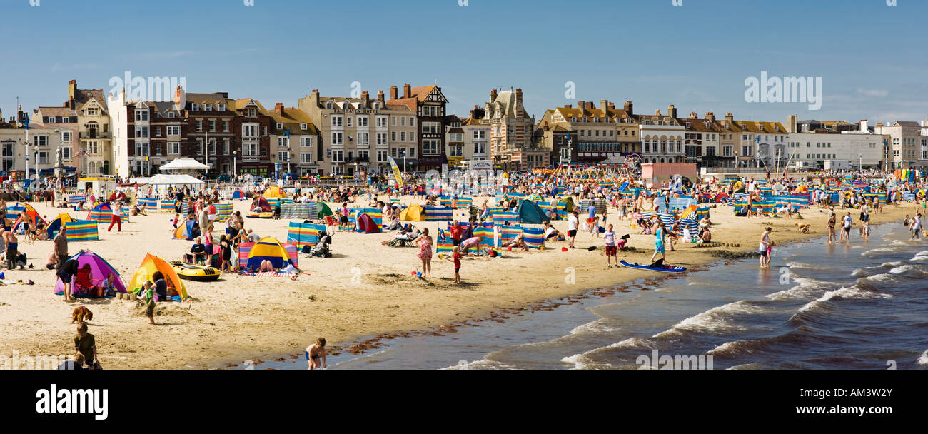 An einem britischen Küste Strand im Sommer, Strand von Weymouth, Dorset, England, UK - Panorama - Menschen, die zum Sonnenbaden und Schwimmen Stockfoto