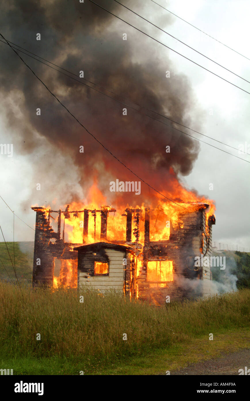 Ein kleines Haus auf den Boden in ein Feuer brennen Stockfoto