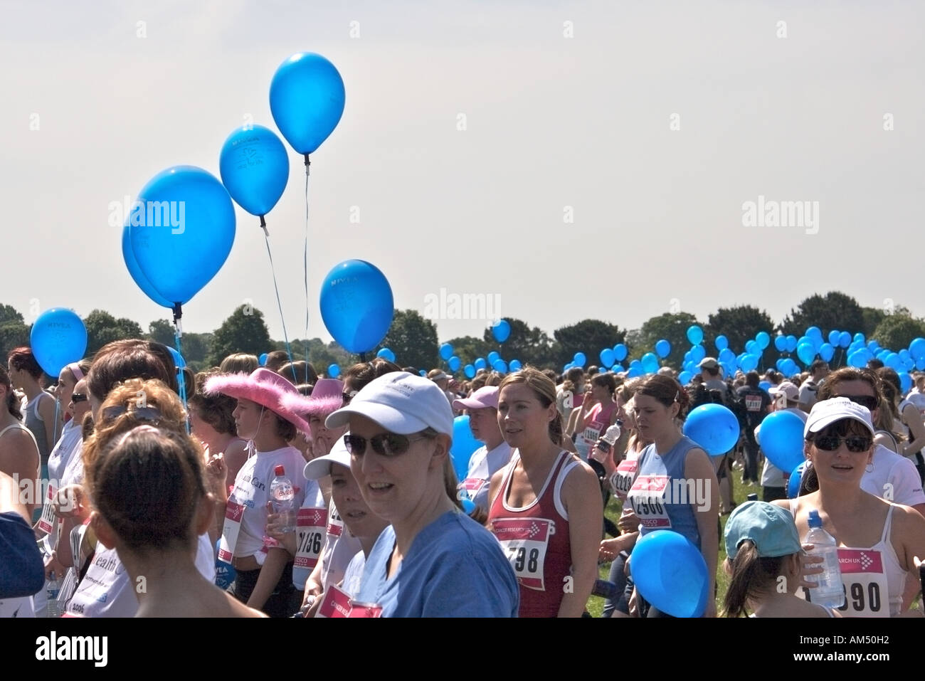 Läuferinnen warten auf den Beginn der jährlichen Veranstaltung "Race for Life" mit blauen gefüllte Heliumballons. Stockfoto