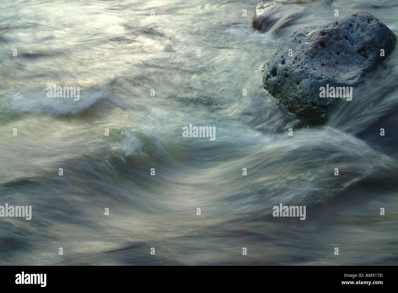 um einen Felsen herum wirbelt rauschende Flusswasser Stockfoto