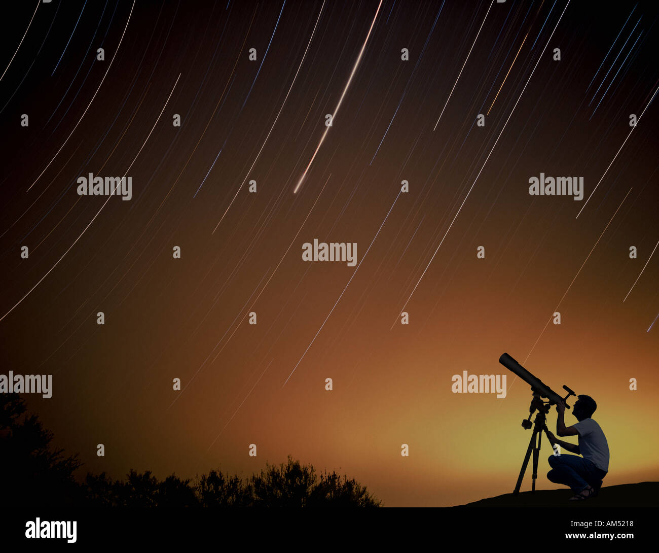Ein Mann mit einem Teleskop schaut in den Nachthimmel. Sternspuren am Nachthimmel, die während einer Langzeitbelichtung. Stockfoto