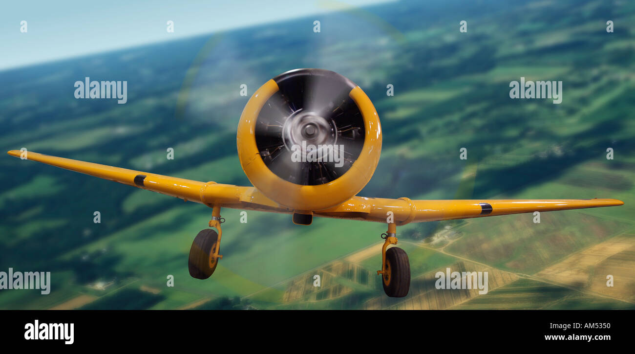 alte gelbe Tiefdecker-Flugzeug fliegen über Felder Stockfoto